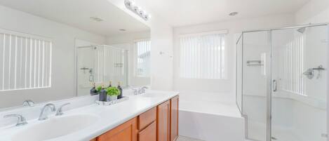 A modern bathroom with two sinks, a large mirror, and a glass-enclosed shower.