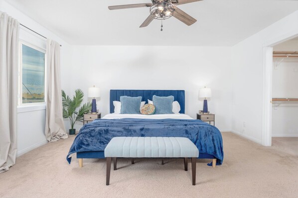 A bedroom with a bed, bedside lamps, a ceiling fan, a window with curtains, and a potted plant. - Stylish & Cozy Home in Coachella (Coachella)
