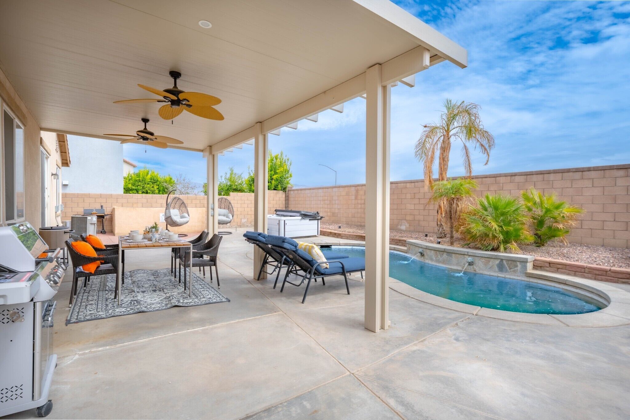 An outdoor patio with a pool, ceiling fans, a grill, and lounge chairs.