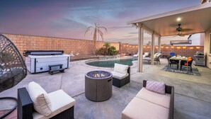 Un espace extérieur aménagé avec une piscine, des chaises longues, un foyer et un coin salon abrité.
