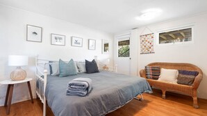 Une chambre à coucher avec un lit, une chaise, une table de chevet et des tableaux encadrés accrochés au mur.