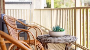 Ein Korbstuhl und ein kleiner Tisch mit einem Blumentopf auf einer Holzterrasse.