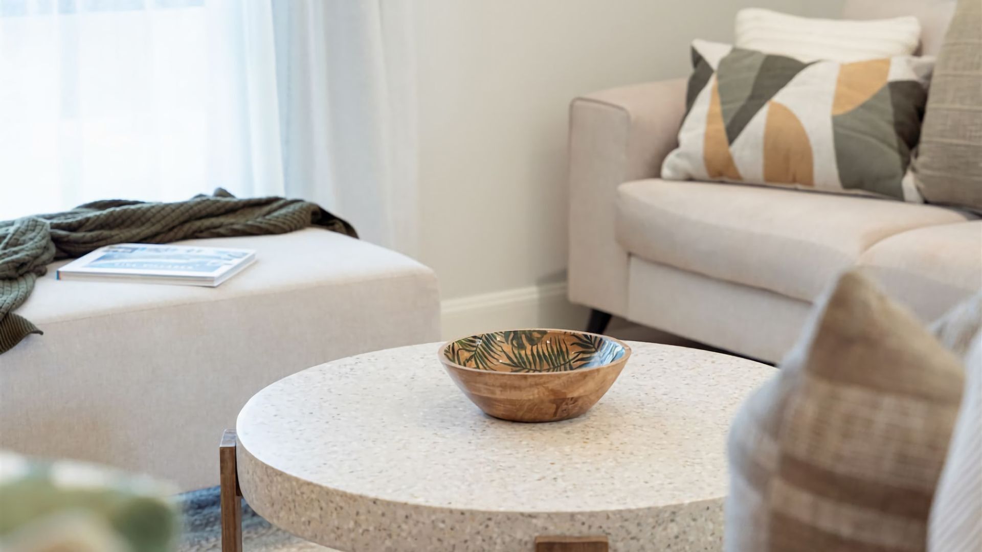 A living room with a round table, a sofa, and a cushion.