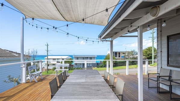 A wooden deck with a view of the ocean and neighboring houses.
