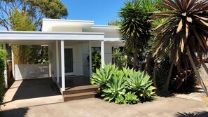 A modern house with a covered porch, a concrete patio, and lush tropical plants. - The Tasman Secret, moments to Manyana Beach (Manyana)