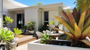 Une maison moderne dotée d’un patio agrémenté de plantes en pot et de mobilier d’extérieur.