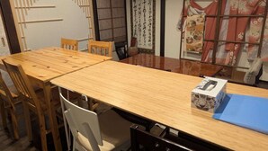 Ein traditioneller japanischer Raum mit Tatami-Bodenbelag, einem Holztisch und einer Schiebetür mit dekorativem Bildschirm.