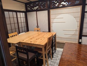 Perinteinen japanilainen huone, jossa on tatamimatto, puinen ruokapöytä ja shoji-liukuovet.