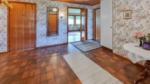 Une pièce spacieuse avec un plancher en bois, un grand tapis et une porte donnant sur un espace extérieur.