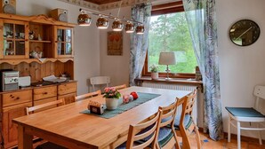 Un coin repas chaleureux avec une table en bois, des chaises et une horloge au mur.