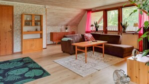 Un salon chaleureux avec un plafond en bois, un canapé, une table basse et un meuble en bois doté d’étagères.