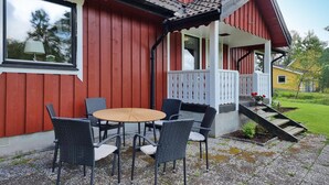 Un bâtiment rouge avec un porche, une table ronde et quatre chaises.