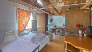 Habitación con dos camas, un escritorio, una silla, una lámpara, un televisor y una ventana con cortinas.