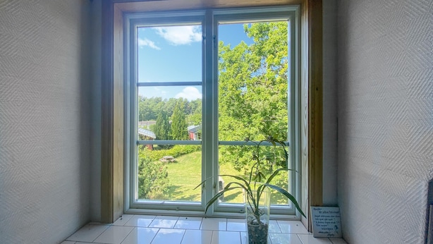 Una habitación con un amplio ventanal corredera que da a un balcón con vistas a un paisaje verde y árboles.