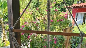 A hammock suspended from a wooden structure in a garden with lush greenery and pink flowers. - Casa Geranios Panajachel (Panajachel)