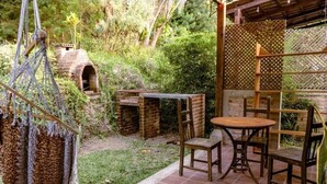 A patio area with a brick oven, wooden chairs, and a table. - Casa Geranios Panajachel (Panajachel)