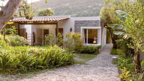 A modern house with a stone pathway leading to a covered patio area. - Casa Geranios Panajachel (Panajachel)