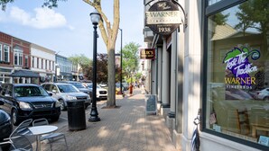 A street with parked cars, a sidewalk, and storefronts including Warner Vineyards.