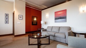 Ein modernes Wohnzimmer mit einem grauen Sofa, einem Glastisch und einer roten Akzentwand.