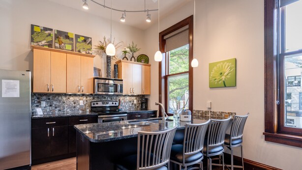A modern kitchen with a central island, bar stools, and a window with a view.