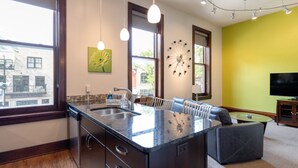 A modern kitchen with a large island, built-in appliances, and a dining area with a sofa and table.