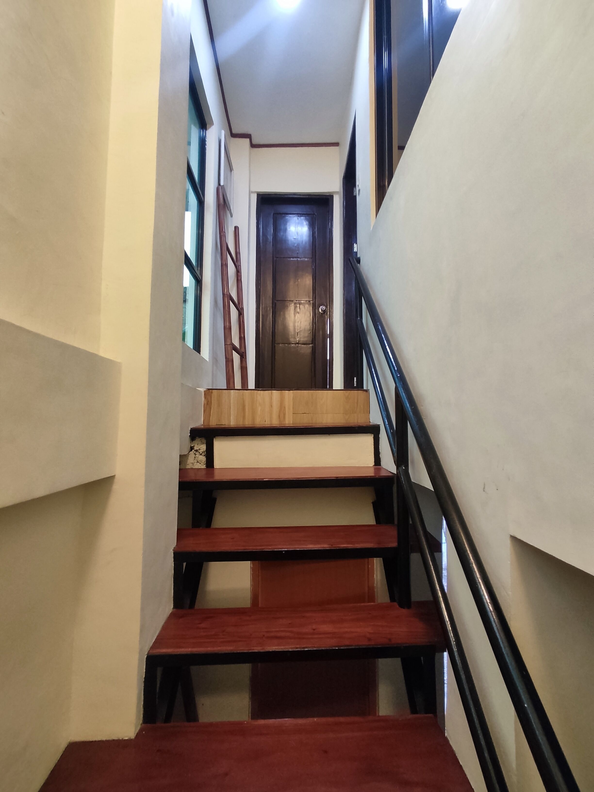 Passadís estret amb una escala de fusta que condueix a una porta al final.