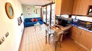A compact kitchen with a dining area, a sofa, and a large window. - Comfortable, equipped stay in a prime area (Las Condes)