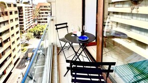 A balcony with a table and chairs, a glass railing, and a view of surrounding buildings. - Comfortable, equipped stay in a prime area (Las Condes)