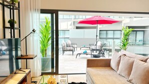 A modern living room with a sofa, coffee table, TV, and potted plants. - SINGULAR DREAM (Playa del Carmen)