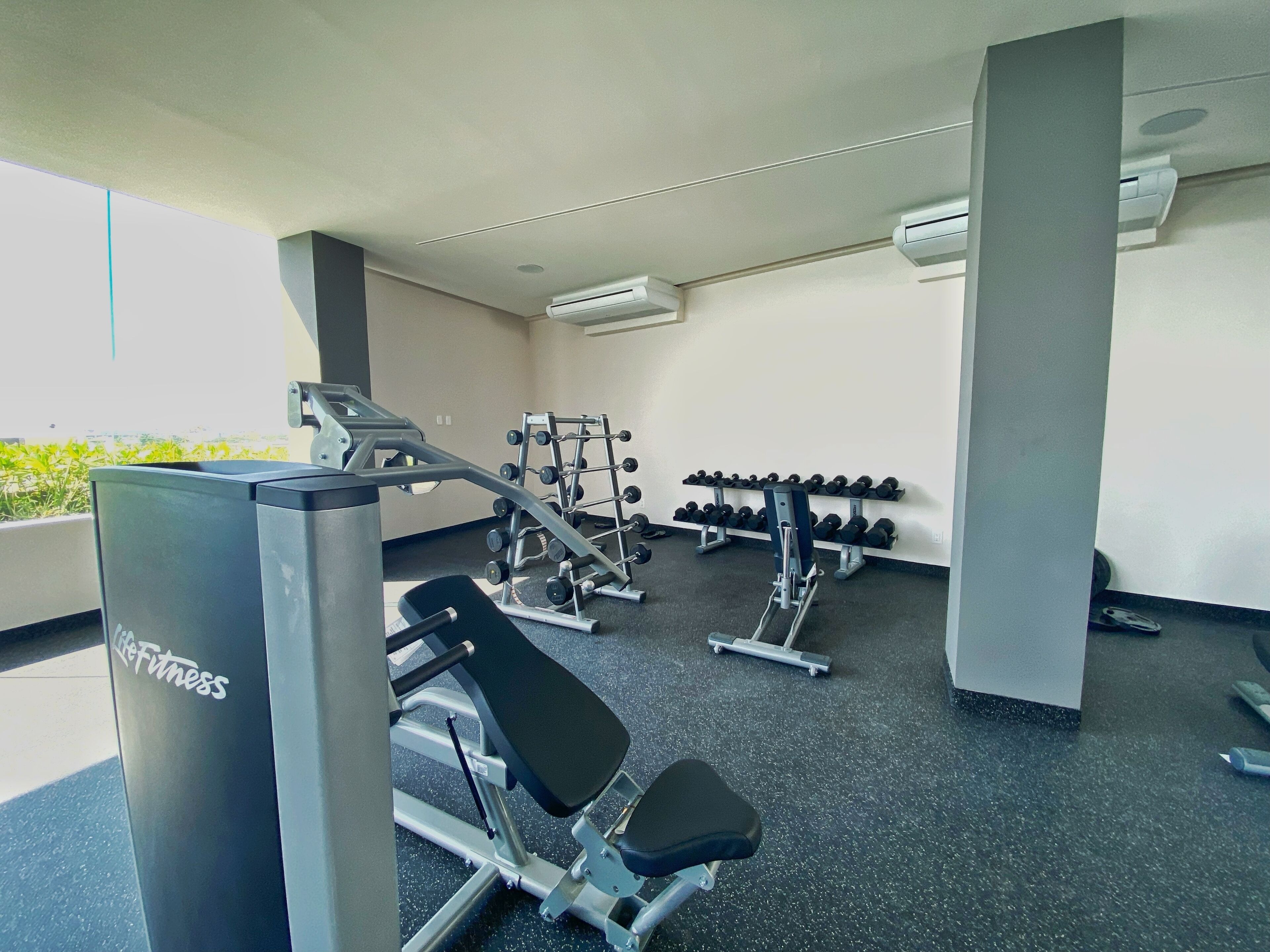 A gym with various exercise equipment, including dumbbells, weight machines, and a bench.