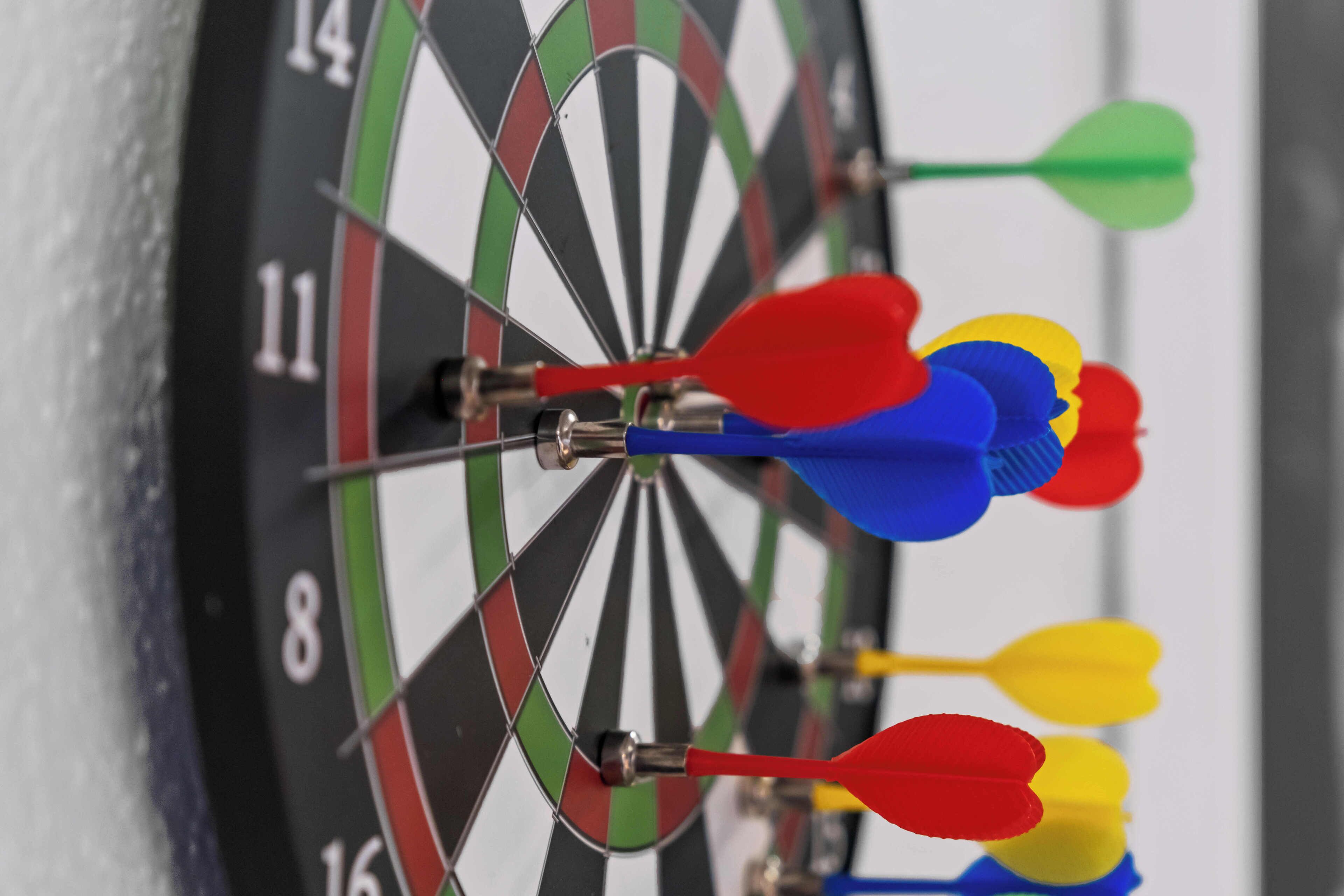 A dartboard with multiple darts stuck in the center.