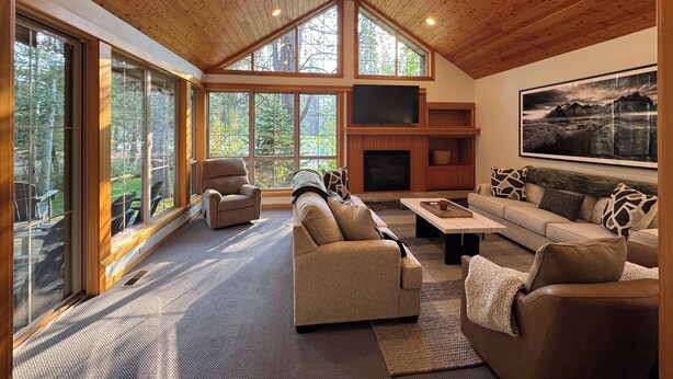 A spacious living room with a high ceiling, large windows, a fireplace, and a mounted TV. - Family Friendly Fremont Crossing Home, 3 Kings, Bunk Room, Hot Tub, SHARC Passes (Sunriver)