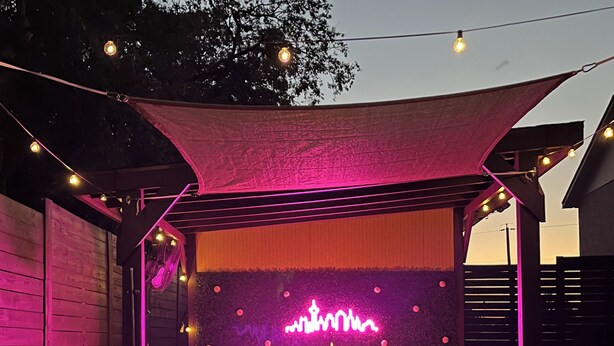 Un jacuzzi con un letrero de neón, rodeado de luces colgantes y un toldo.