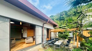 A modern house with large glass doors leading to a living area with a sofa and a dining table. - Fumiko-no-tei Residence with a view of the sea Max. 17 - 34 people OK. garden BBQ (西牟婁郡白浜町)