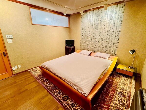 A bedroom with a bed, a television, a lamp, and a window.