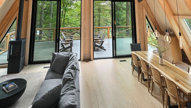 Um amplo loft com pé direito alto, grandes janelas, um espaço de jantar em madeira e uma área de estar aconchegante.
