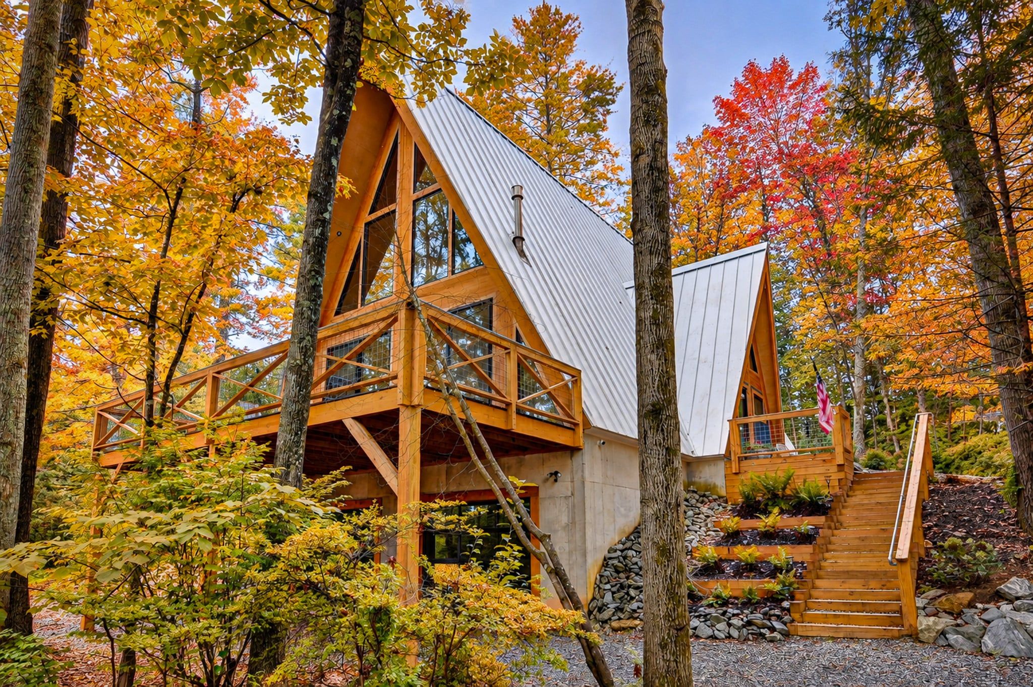 A cabin with a sloped roof, wooden beams, and a staircase leading to a deck.