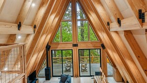 Um amplo loft com pé direito alto e janelas grandes, destacando um interior em madeira e vista para o exterior.