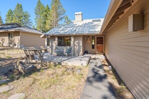 A single-story house with a covered patio, a front door, and a small porch with two chairs. - 15 Lassen - Charming, Hot Tub, SHARC, A/C (Sunriver)
