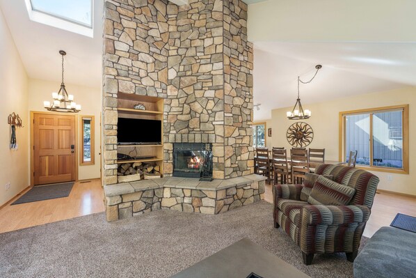 A living room with a stone fireplace, a television, and a comfortable seating area. - 15 Lassen - Charming, Hot Tub, SHARC, A/C (Sunriver)