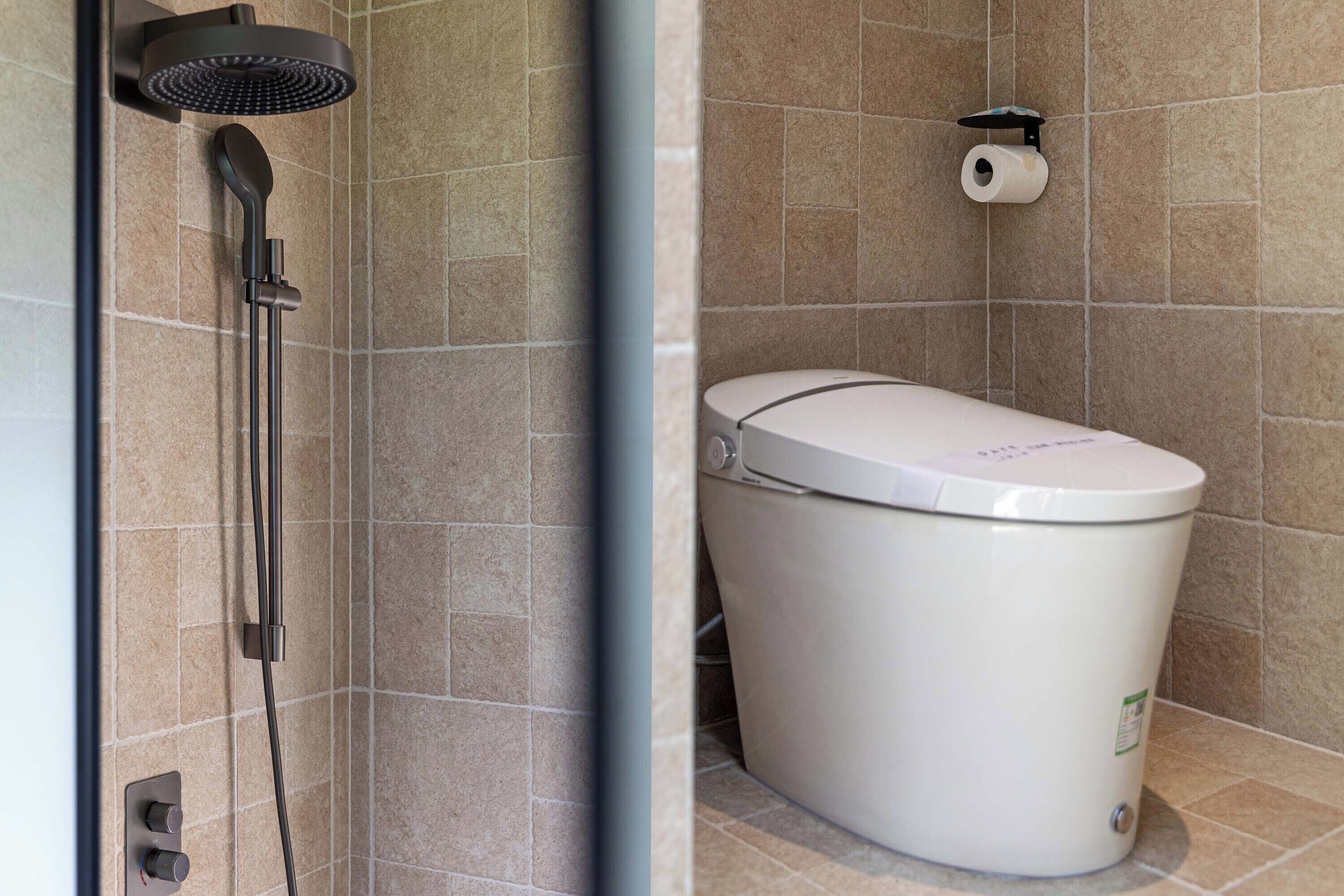 Un baño con ducha moderna, inodoro y dispensador de papel higiénico en la pared.