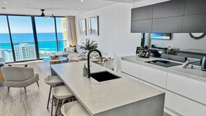 A modern kitchen with a large island, bar stools, and a view of the ocean. - Luxury Oracle Tower 2 Ocean Views 22nd floor (Broadbeach)