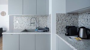 Une petite cuisine équipée d’un évier, d’une bouilloire et d’un grille-pain posés sur le plan de travail.