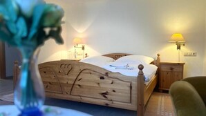 En træseng med sengegavl, to natborde med læselamper og en grøn stol.