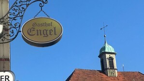 En bygning med et tårn med et ur og et skilt, der siger "Gasthof Engel".