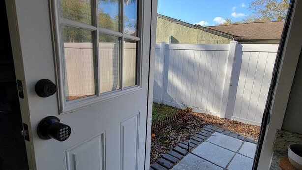 A white door with a glass panel, a black doorbell, and a doormat.