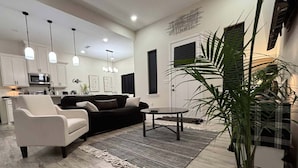 Un salon moderne avec un canapé, un fauteuil, une table basse et une grande plante en pot.