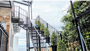 A staircase with metal railings leading to a balcony with potted plants.