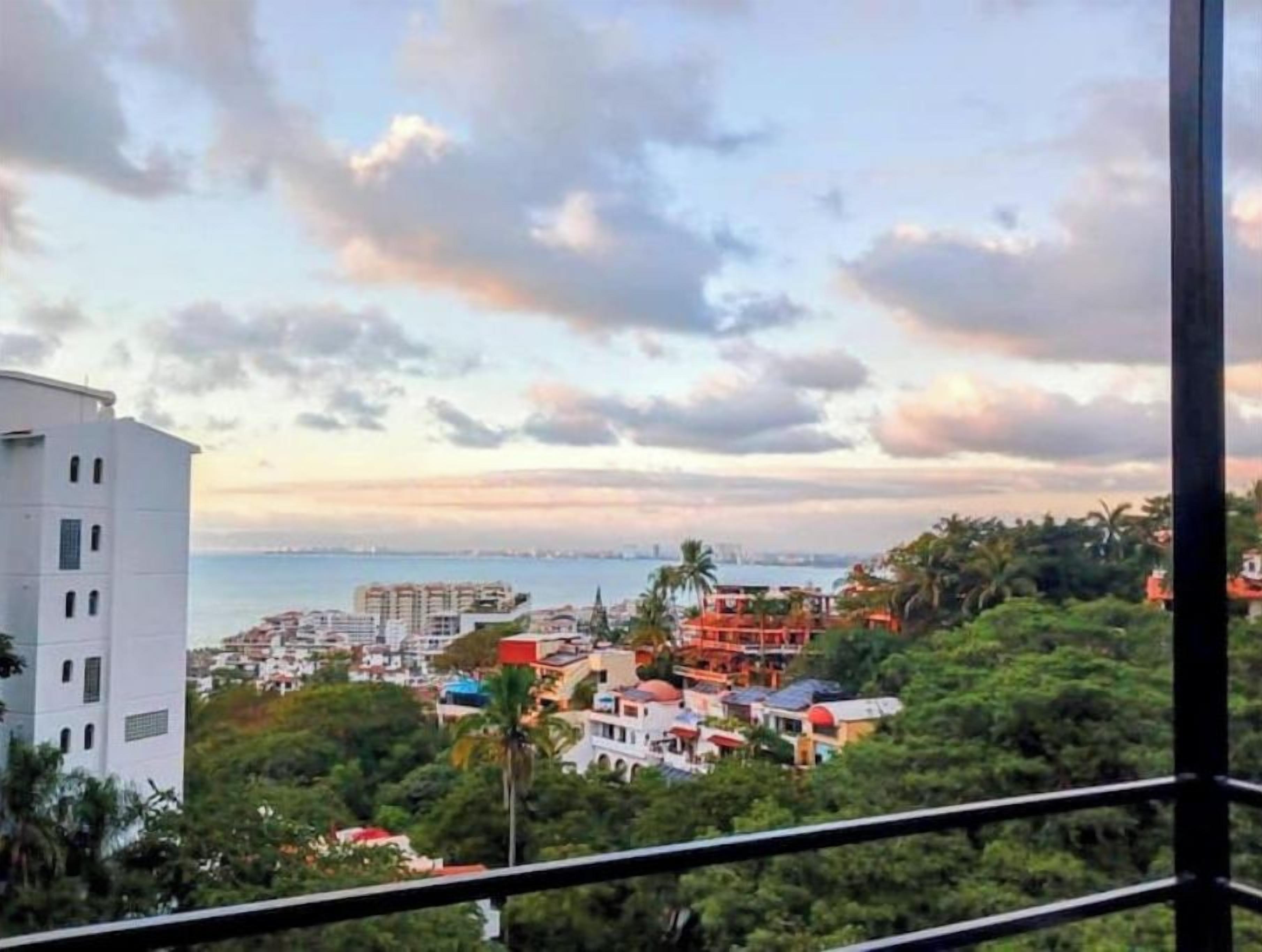 Un paysage urbain côtier avec des bâtiments, de la végétation et une vue sur la mer.