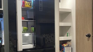 A compact kitchen with a black refrigerator, a microwave, and a built-in oven. There is a small pantry with shelves and a door. - Convenient to UA, Northport and Mercedes (Tuscaloosa)